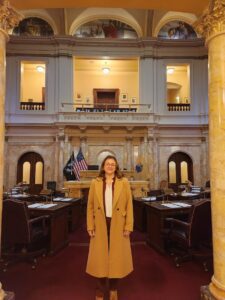 Person standing in a grand legislative chamber.