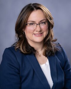 Woman in glasses with a blue blazer.